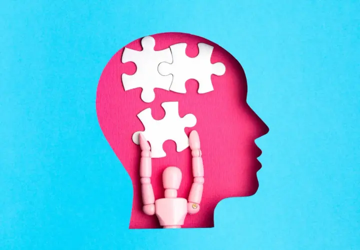 Drewniany ludzik układa puzzle w głowie, symbolizując otwarty umysł i proces myślowy.
