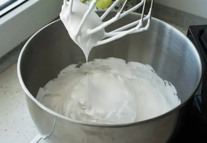 Ubita śmietana z mascarpone, puszysta i idealna do deserów, właśnie powstaje w metalowej misie miksera.