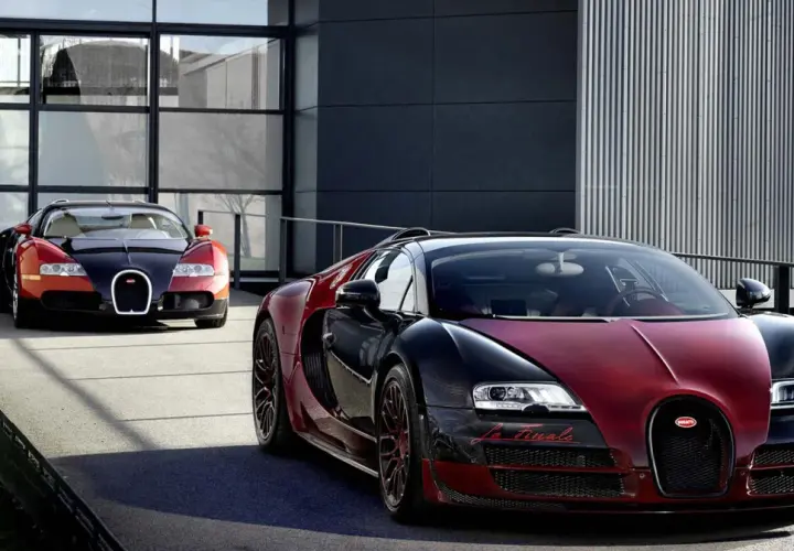 Dwa Bugatti Veyron w kolorach czarnym i czerwonym przed nowoczesnym budynkiem.