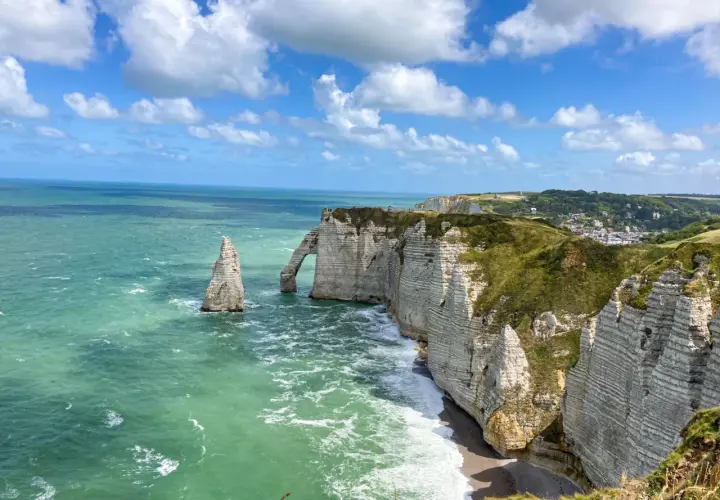 Klify w Étretat, Normandia: białe skały, łuk skalny i iglica w zielonym morzu.