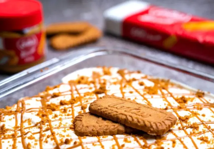 Postre cremoso decorado con galletas y caramelo, con un tarro y paquete de **lotus biscoff ingredients** al fondo.