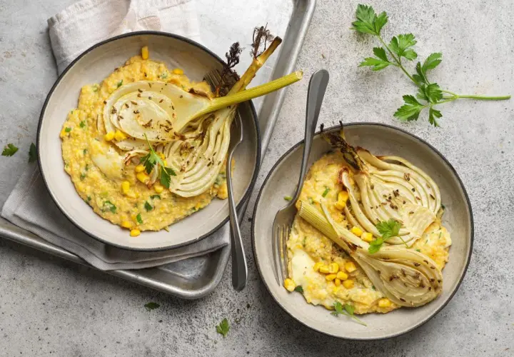 Deux bols de polenta crémeuse avec du fenouil rôti, du maïs et du persil.