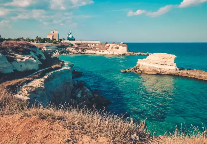 Côte rocheuse italienne aux eaux turquoise, avec des falaises et des formations rocheuses dans la mer.