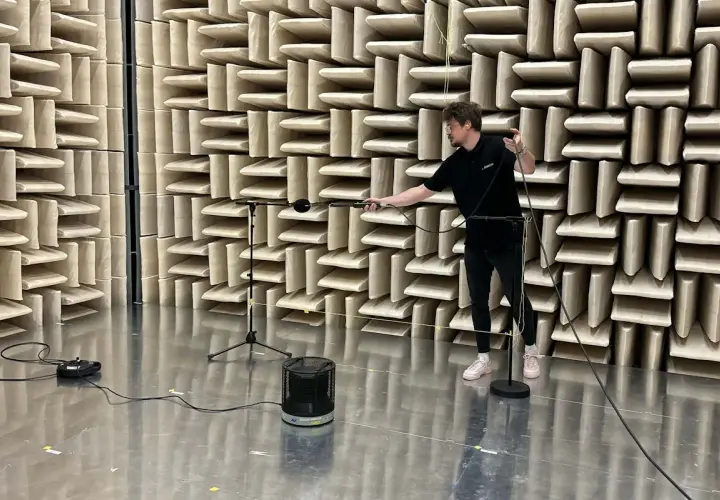 Hombre ajustando micrófonos en cámara anecoica para medir la unidad de potencia acústica de un altavoz.
