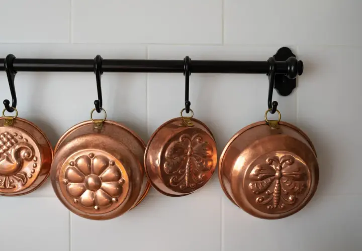 Cuencos de cobre decorados cuelgan de una barra. Aprende como limpiar cobre para que brillen así.