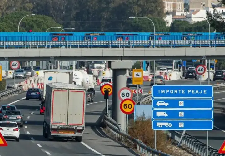 Tráfico lento en peaje con señales de límite de velocidad y de carril estrecho. Los vehículos esperan para pagar el importe del peaje.