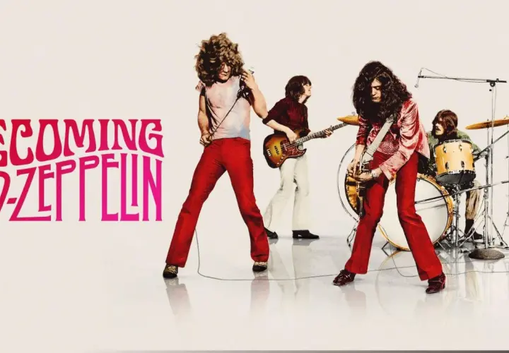 Zespół Led Zeppelin w akcji. Wokalista z mikrofonem, gitarzysta, basista i perkusista tworzą potężne brzmienie.