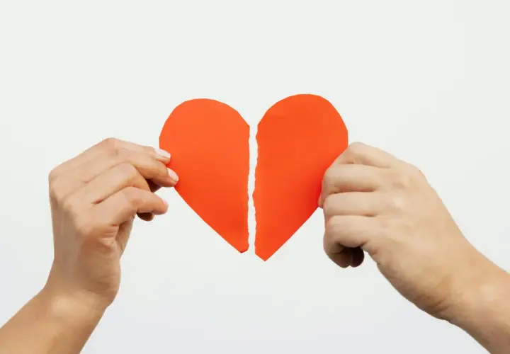 Mani che tengono un cuore rosso spezzato. Ho perdonato un tradimento ma non riesco a dimenticare.