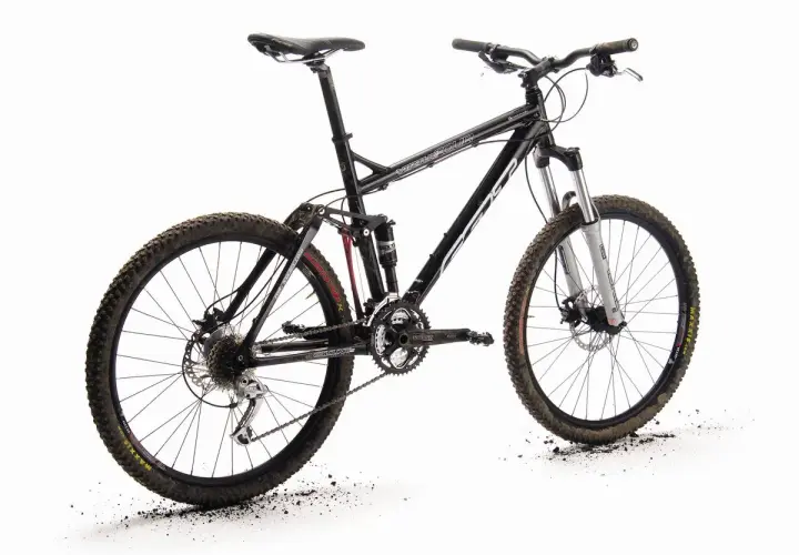 A black full-suspension mountain bike, the "Felt Virtue," stands ready for adventure. Its knobby tires are dusted with dirt, hinting at recent trails.