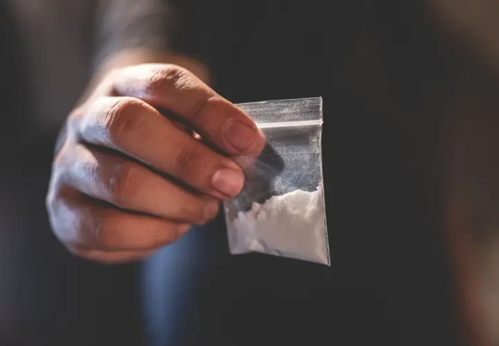 Dłoń trzyma woreczek z białym proszkiem. To może być związane z chemsex, czyli używaniem substancji psychoaktywnych w celu wzmocnienia doznań seksualnych.