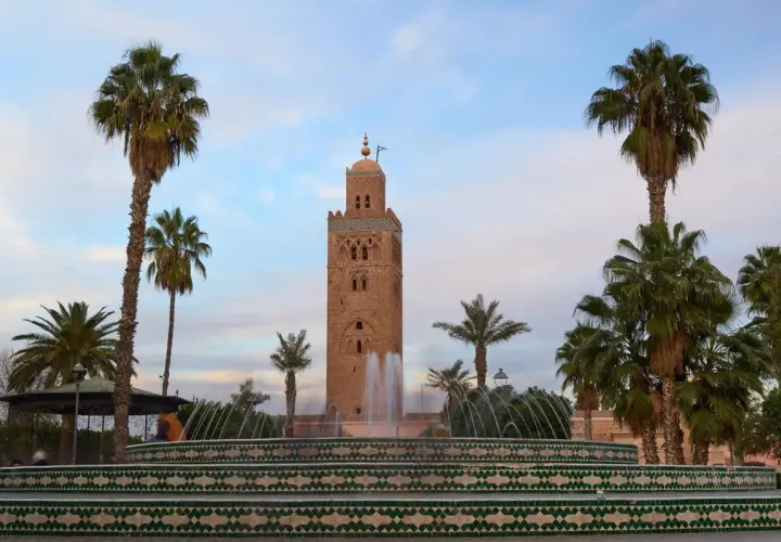 Torre Koutoubia y fuente en Marrakech, un lugar perfecto para tu visita de Marrakech en 3 días. Palmeras y cielo azul.