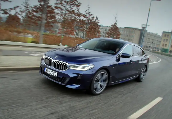 Granatowe BMW 640i sunie po miejskiej drodze, ukazując swoje eleganckie linie i sportowy charakter.