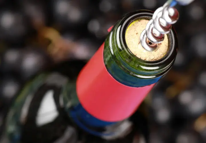 Ein Korkenzieher öffnet eine Flasche Wein, bereit für den Genuss. Ein Glas Wein am Tag hält den Arzt fern.