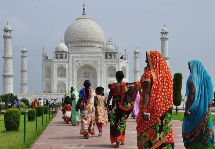 Tłum turystów, w tym kobiety w barwnych sari, zwiedza Taj Mahal. Zastanawiasz się, ile kosztuje wiza do Indii, by zobaczyć to cudo?