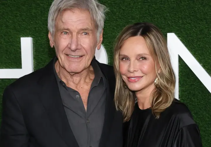 Harrison Ford z żoną Calistą Flockhart na tle zielonej ściany z białymi literami.