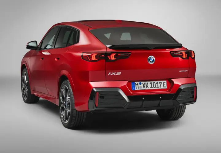 Czerwone BMW iX2 z napisem "XDrive30" na klapie bagażnika, z tyłu widoczne są lampy LED i tablica rejestracyjna.