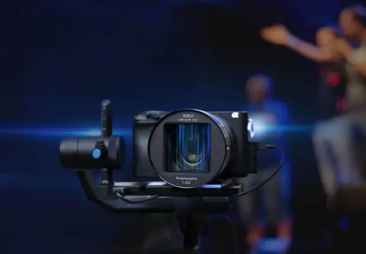 Kamera z obiektywem anamorficznym 1.33X na stabilizatorze, gotowa do uchwycenia dynamicznej sceny z ludźmi w tle.