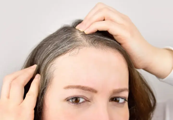 Mujer revisando sus canas, pensando en un baño de color para canas.