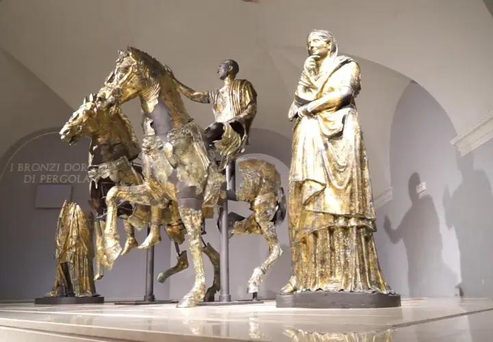 Bronzi dorati di Pergola: un cavaliere su un cavallo, una figura femminile e altre statue antiche.