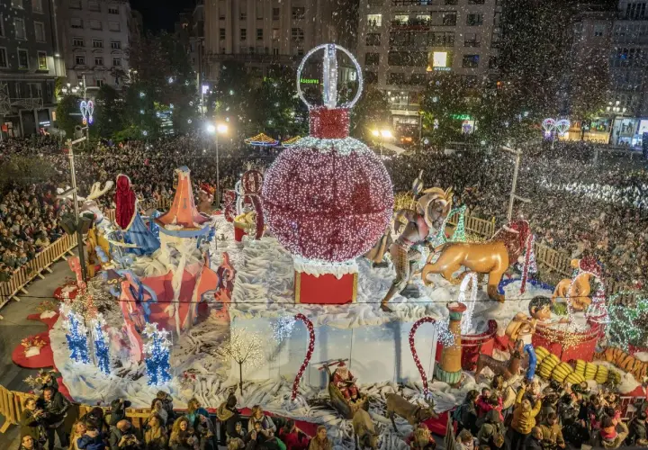 Desfile navideño en Santander con un gran adorno de bola de Navidad y figuras, rodeado de gente y confeti. Encendido luces Santander.