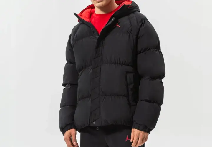 Mężczyzna w czarnej, puchowej kurtce Jordan Essentials z czerwonym wykończeniem i logo Jumpman.