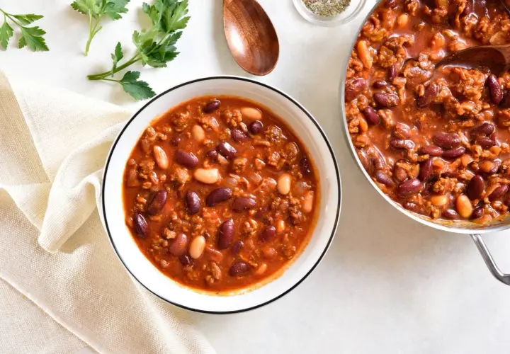 Aromaticzna zupa meksykańska z kurczakiem, pełna fasoli i mielonego mięsa, podana w misce i garnku.
