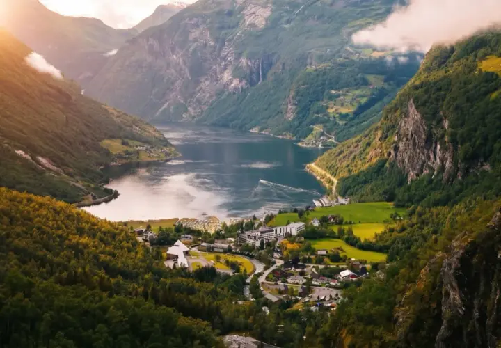 Malowniczy fiord w Norwegii, z zielonymi zboczami gór, wodospadami i małą wioską. Klimat tego miejsca sprzyja podziwianiu natury.