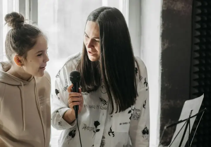 Kobieta i dziewczynka ćwiczą śpiew, tworząc piękny **rezonans dźwięków**.