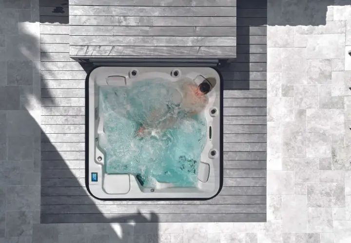 Un homme profite d'un traitement spa relaxant dans un jacuzzi bouillonnant, entouré de bois et de pierre.