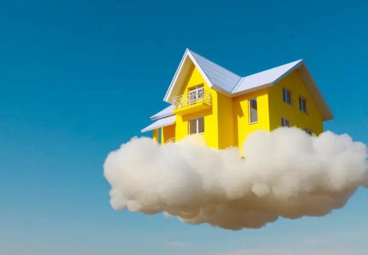 Una casa amarilla con techo blanco flota sobre una nube, como si fuera un sueño con el interior de una casa.