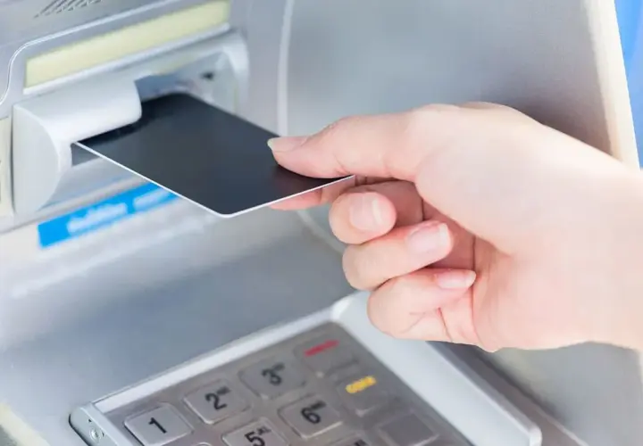 Wkładanie karty do bankomatu. Planując podróż, warto sprawdzić, czy w Norwegii można płacić euro.