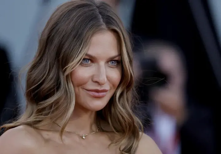 Anna Lewandowska, znana dziennikarka, zjawiskowo prezentuje się na czerwonym dywanie. Jej błękitne oczy przyciągają uwagę.