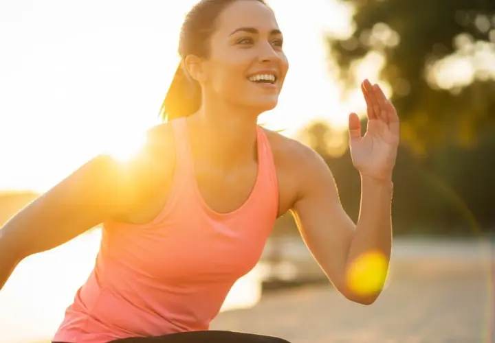 Mujer sonriente corriendo al atardecer, un secreto para como mantenerse joven es la actividad física y disfrutar del sol.