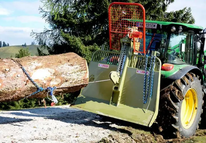 Ein Traktor mit einer **seilwinde** zieht einen Baumstamm aus dem **Wald**.