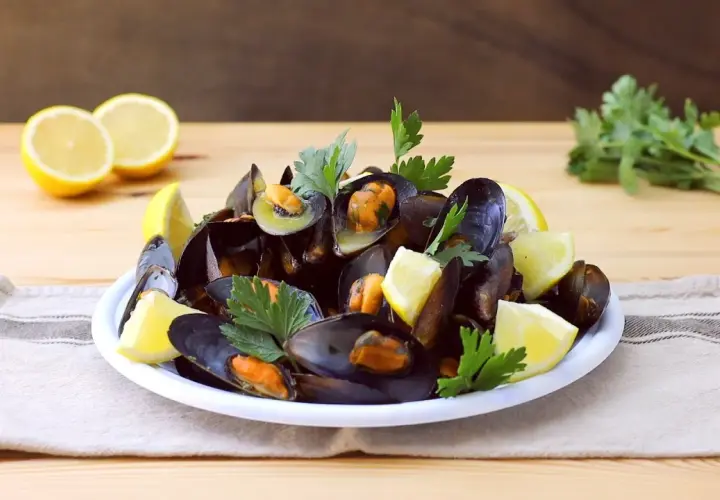 Un piatto fumante di impepata di cozze, guarnito con limone fresco e prezzemolo, pronto per essere gustato.