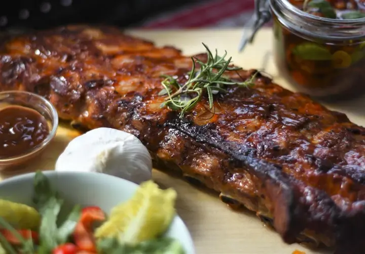 Un ribs de porc laqué, garni de romarin, avec une sauce barbecue, de l'ail et une salade fraîche.