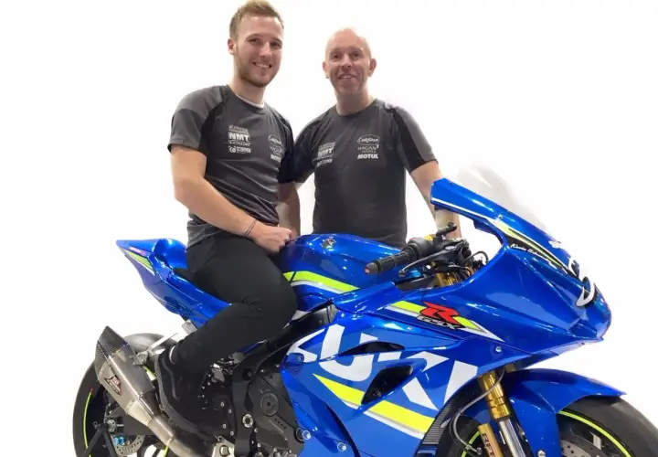 Davey Todd y su equipo posan junto a una moto Suzuki azul brillante.
