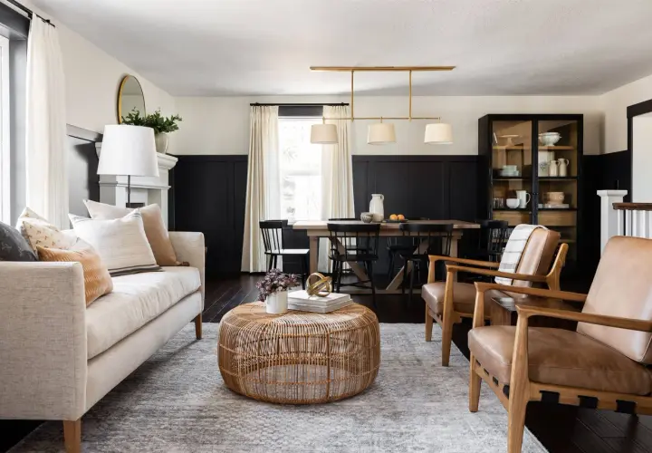 A living and dining space with a neutral palette and natural textures, embodying the mcgee and co style. A light-colored sofa, rattan coffee table, and leather armchairs create a cozy seating area.