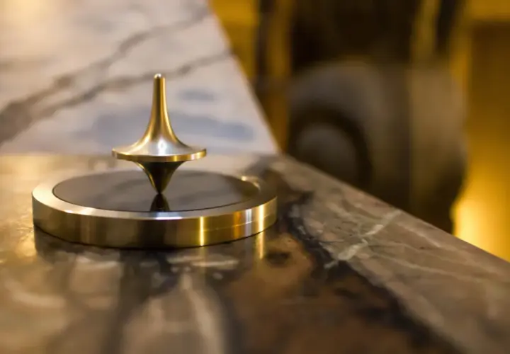 Toupie dorée en rotation, un exemple de force centrifuge qui maintient son équilibre.