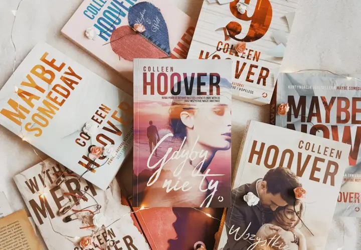 Książki Colleen Hoover ułożone na jasnym tle, ozdobione światełkami i sztucznymi kwiatami. Wśród nich "Gdyby nie ty", "Maybe Someday" i "Wszystkie nasze obietnice".