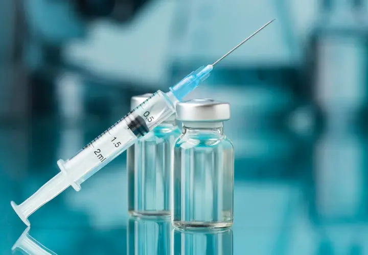 Strzykawka z igłą opiera się o fiolki. Może to być nalokson, lek ratujący życie w przypadku przedawkowania opioidów.