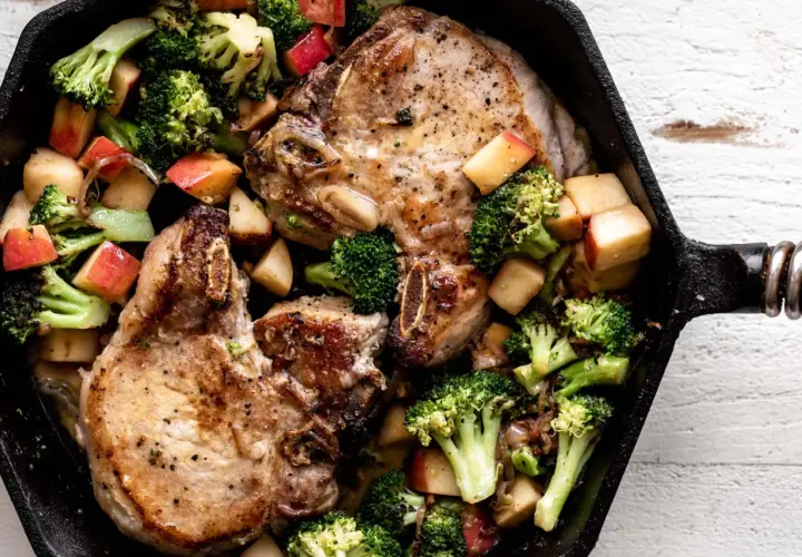 Juicy miso pork chops with roasted broccoli and apple chunks in a cast iron skillet.