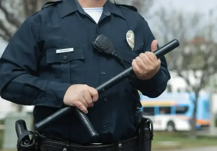 Ochroniarz z pozwoleniem na broń trzyma pałkę. Zastanawiasz się, ile zarabia ochroniarz z pozwoleniem na broń?