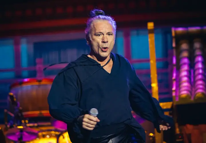 Bruce Dickinson, wokalista Iron Maiden, śpiewa z mikrofonem na koncercie.