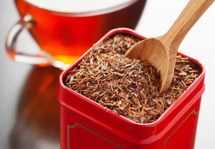 Czerwona herbata rooibos w metalowym pudełku, gotowa do zaparzenia. Bez kofeiny, idealna na relaks.