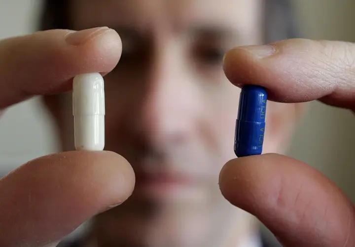 Dita tengono una pillola bianca e una blu, forse per uno studio sull'effetto placebo.