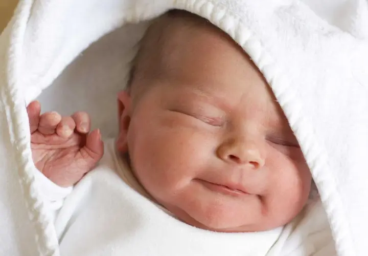 La morbida pelle neonato, avvolta in un soffice asciugamano bianco, dorme serenamente.