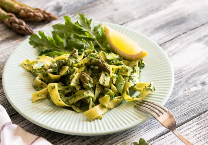 Pappardelle z zielonym sosem, szparagi i rukola na talerzu. Pyszny makaron ze świeżymi warzywami.