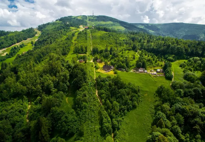 Widok z lotu ptaka na zielone zbocza Skrzycznego z kolejką linową i domkami.