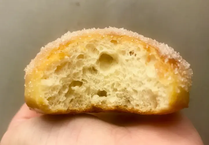 Gros plan d'un beignet sucré, sa mie aérée parfaite pour une recette beignet maison.